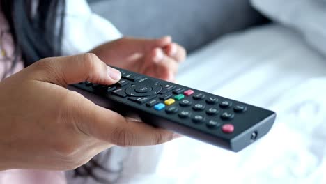 person holding a tv remote in a bedroom