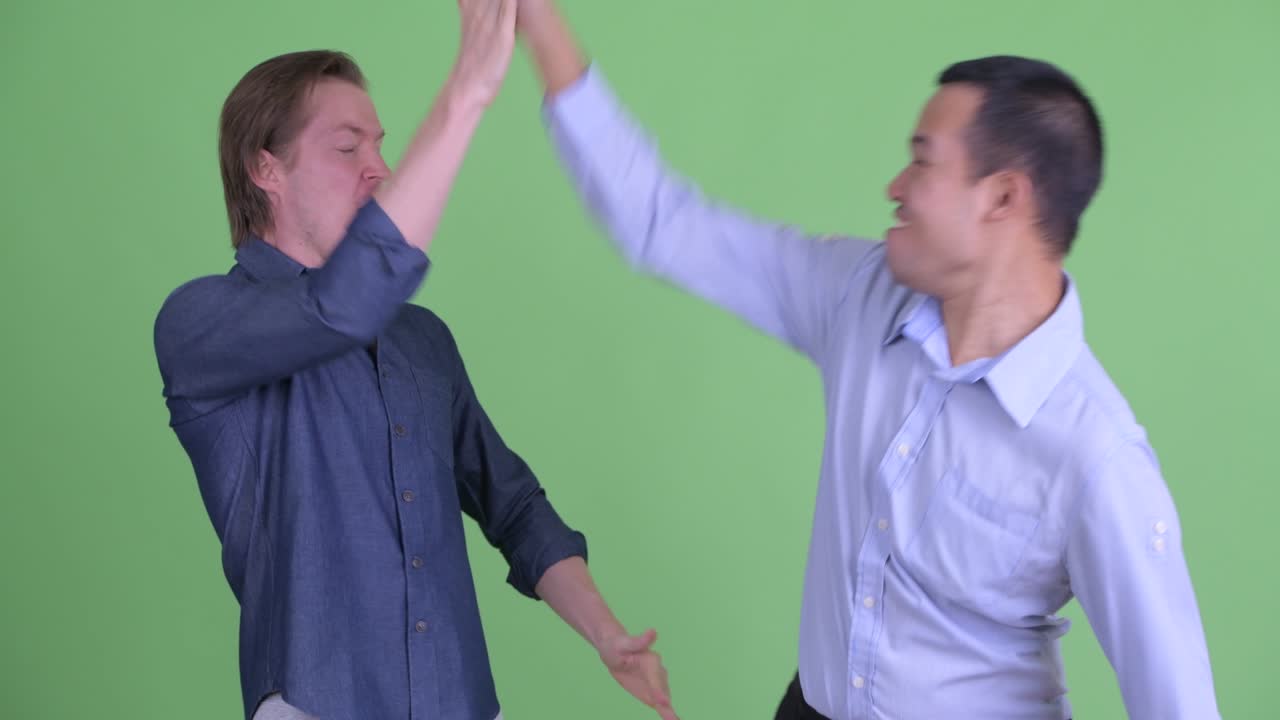 초록색 스튜디오 배경에 매우 흥분하고 행복해 보이는 두 사업가