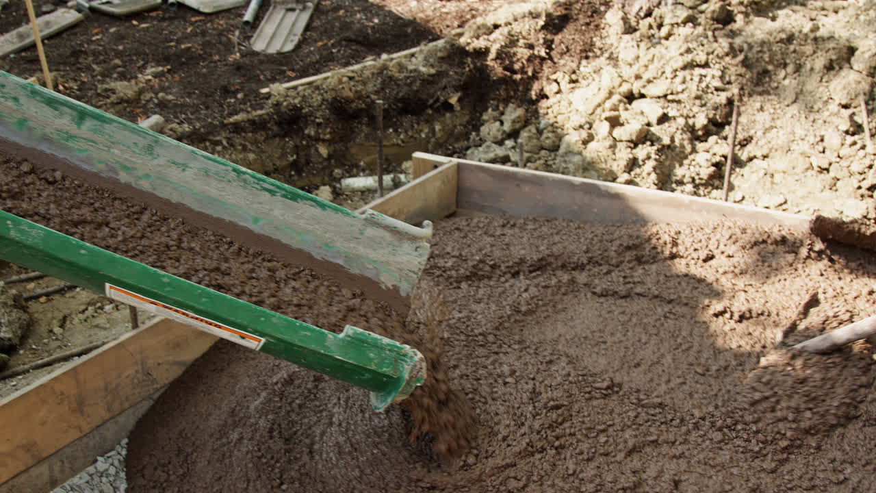 Workers Pouring and Spreading Fresh Concrete on a Construction Job Site