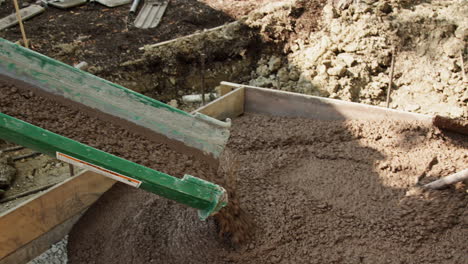 workers pouring and spreading fresh concrete on a construction job site