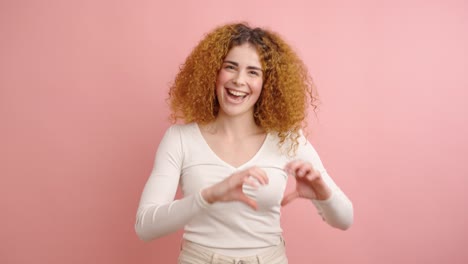 joyful woman laughing and gesturing against pink background
