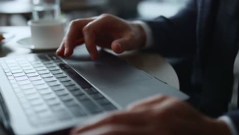 Man-hands-working-computer-online-using-touchpad-browsing-business-news-in-cafe.