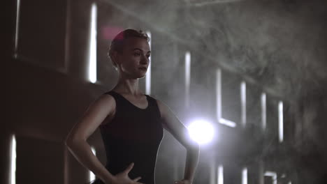 movimiento lento: diligente joven bailarina graciosa bailando elementos de ballet clásico en la oscuridad con luz y humo en el fondo. hermosa joven bailarín en la oscuridade.