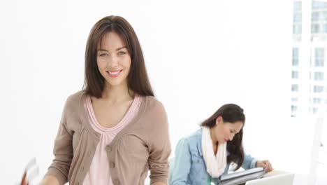 creative businesswoman smiling at camera with colleague behind her