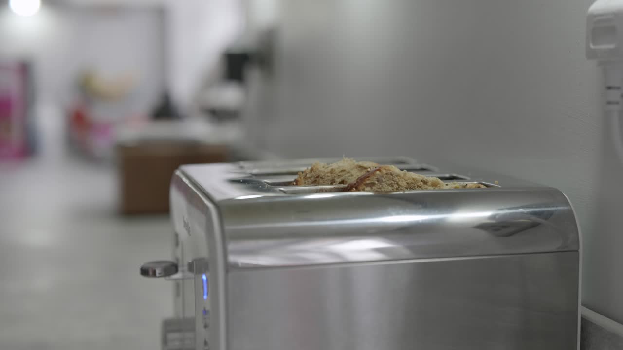 un hombre pone dos rebanadas de pan en una tostadora en la cocina de casa