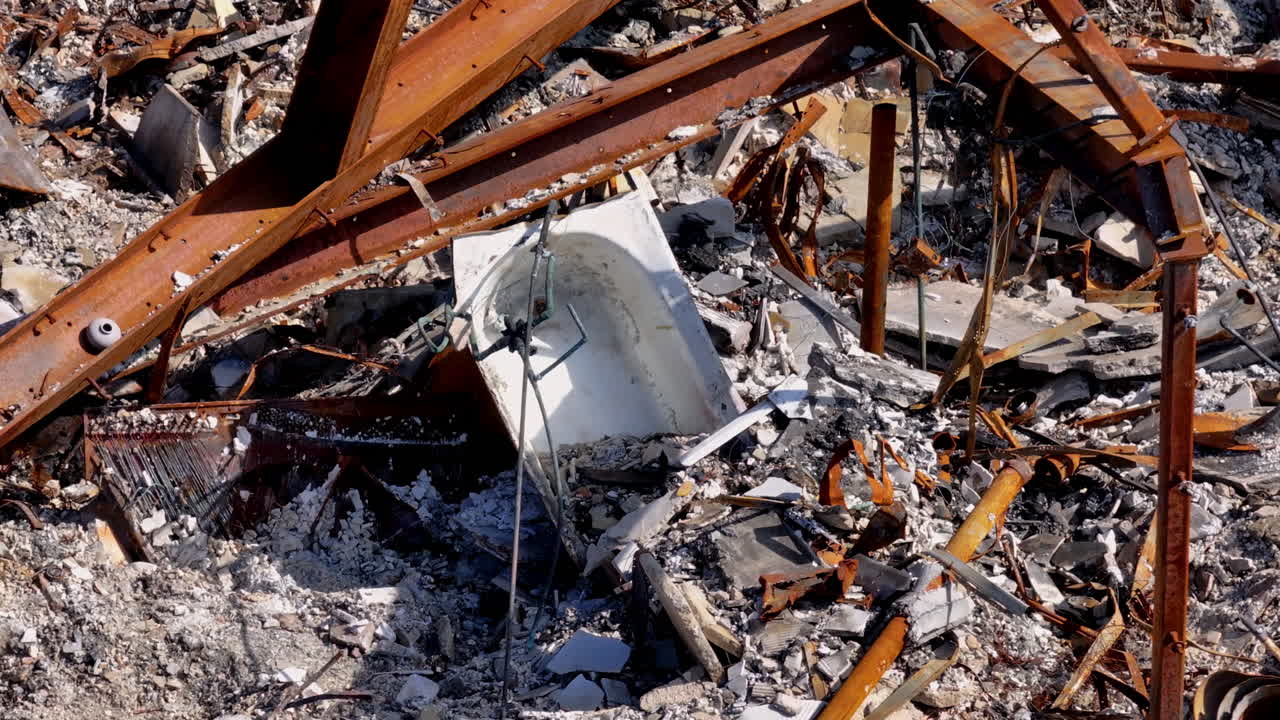 Scene of complete demolition featuring a bathtub among rubble and rusty beams