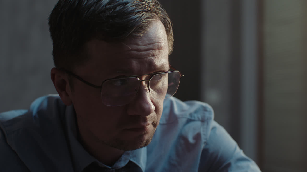 A sad man in a shirt slowly eats breakfast