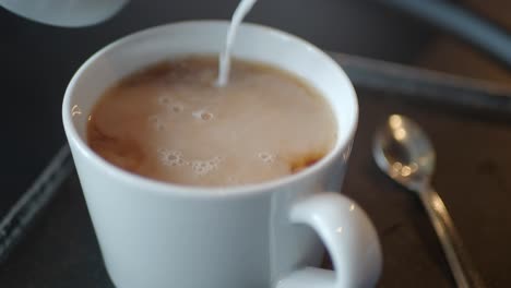 pouring milk into a cup of tea