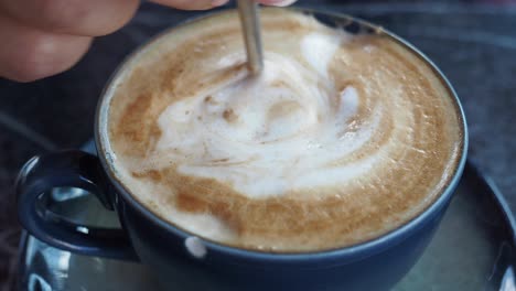 hand stirring a cappuccino