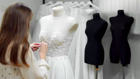 portrait of a girl creating a wedding dress by exclusive order sewing fabrics and rhinestones on a dress dressed in a mannequin. production of wedding dresses. little business