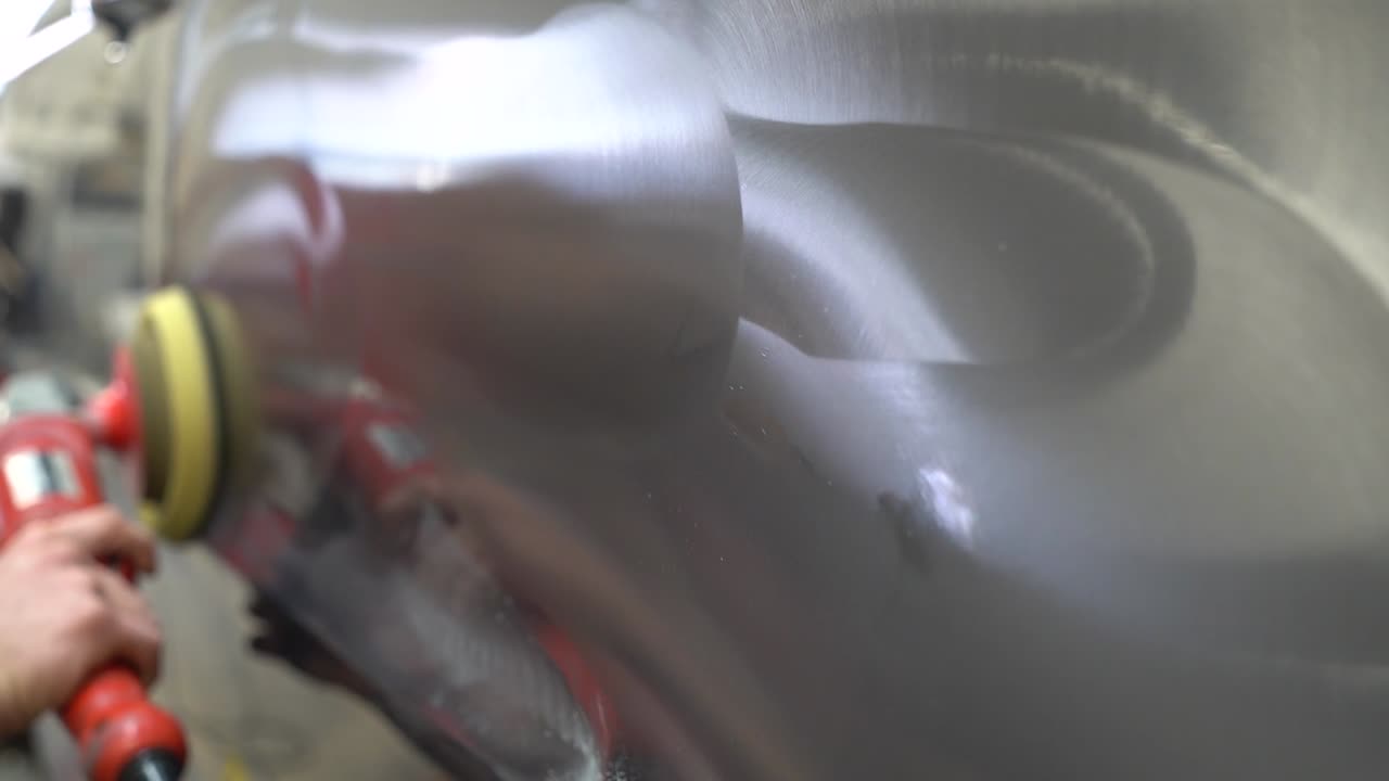 Male worker using a polisher to polish a black car