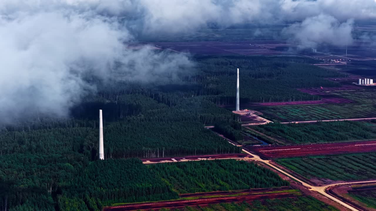 Aerial shot of wind turbines and dark clouds above green farmlands