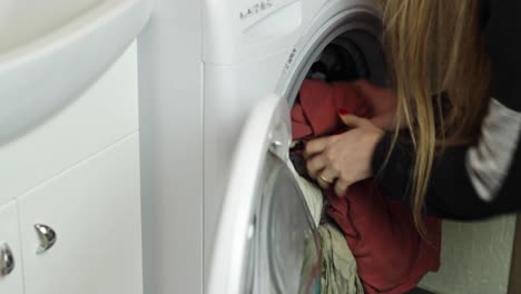 static view of a woman opening and unloading a washing machine load into a basket underneath