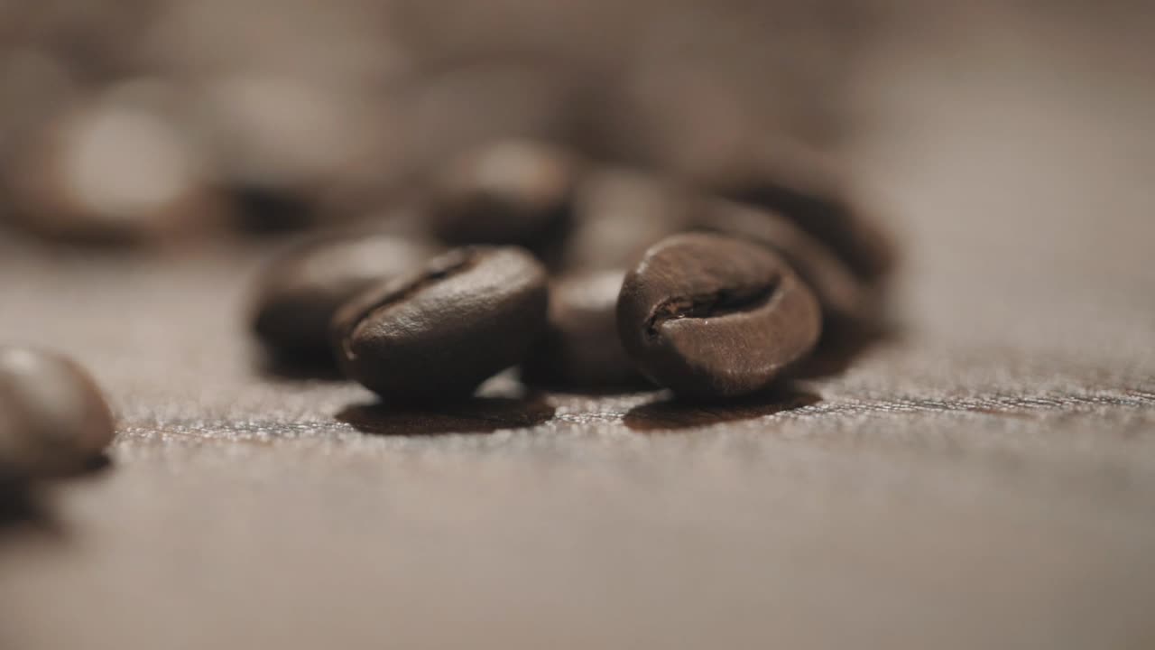 Friske kaffebønner spredt ud over et træbord i slowmotion