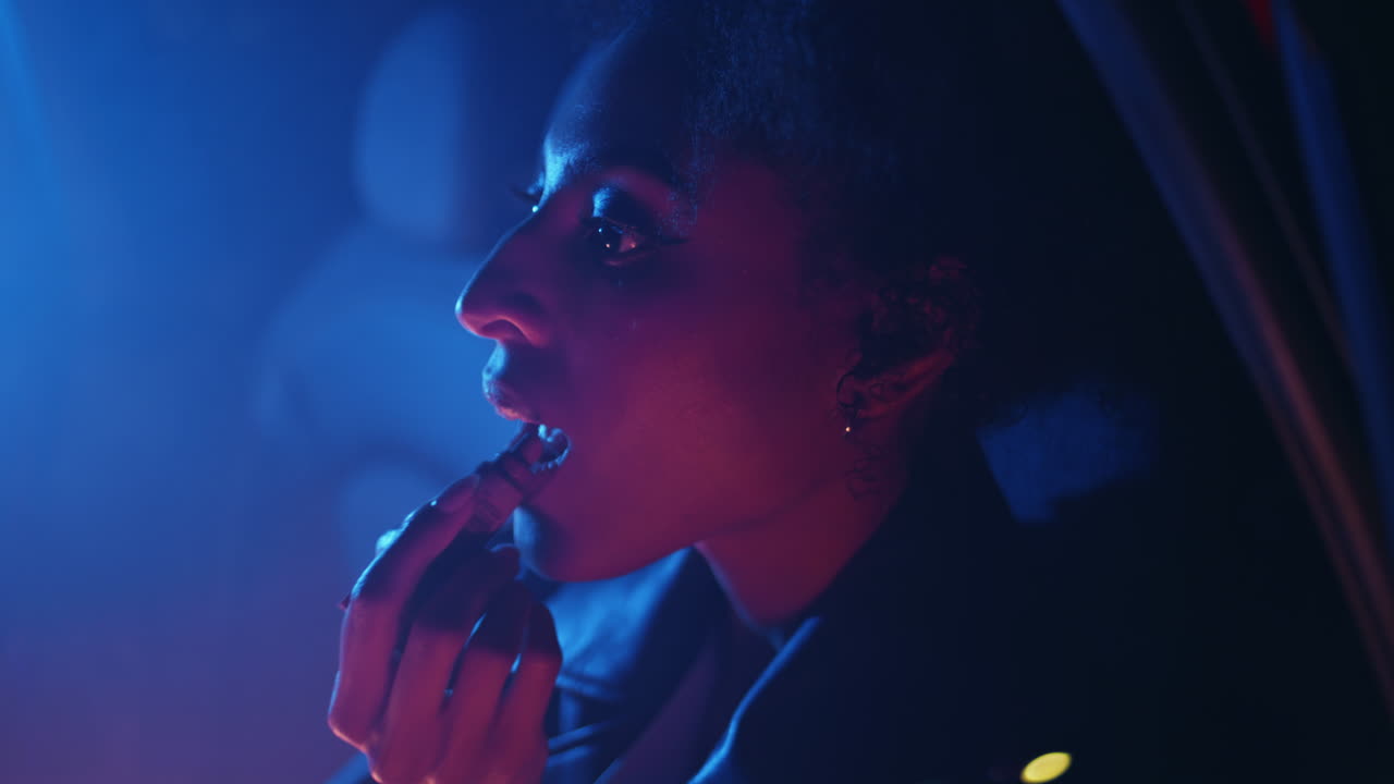Calm girl painting lips sitting car in glowing neon lights closeup. Trendy woman
