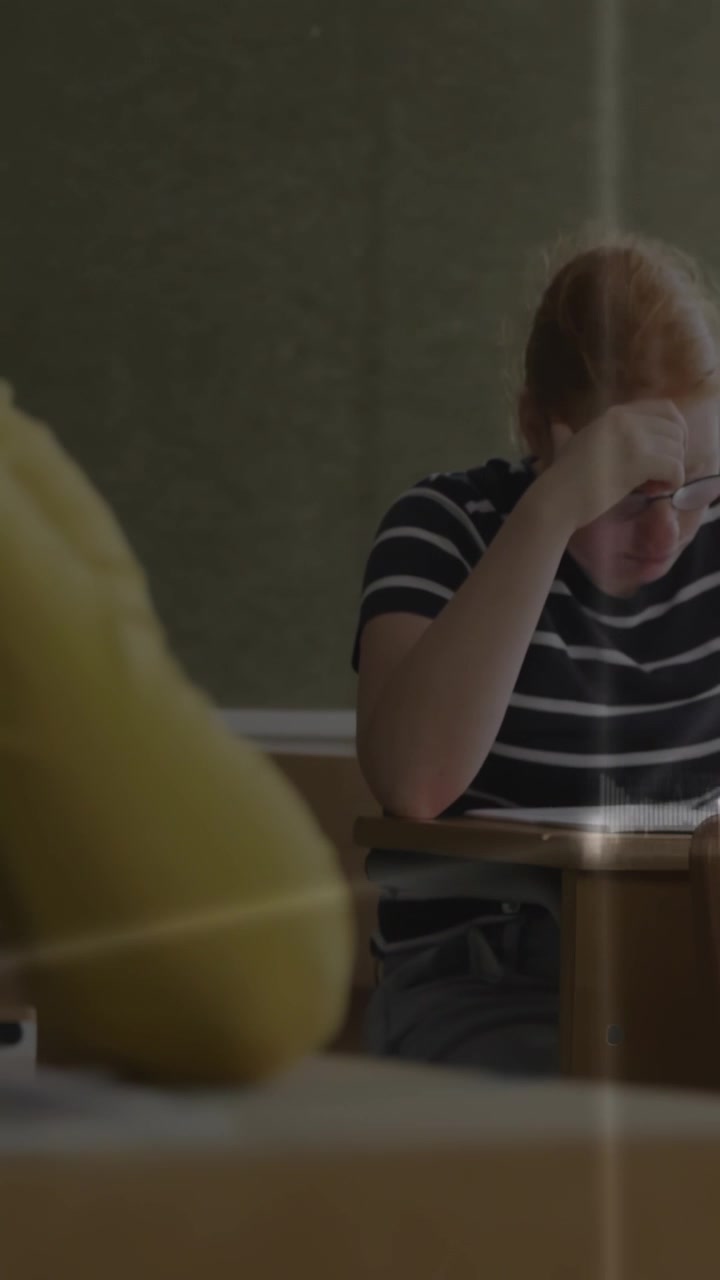 Video verticale: Studente adolescente che inizia un esame, chinato sul foglio, linee HUD che si allineano vicino alla testa.