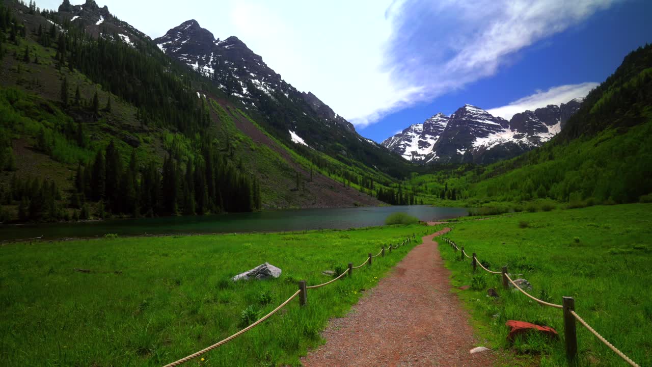 Spring summertime sunny blue sky morning Maroon Bells Peaks Maroon Lake Trail wilderness Colorado North Maroon Pyramid Peak14er blue sky high clouds scenic landscape fencing to lakefront pan right
