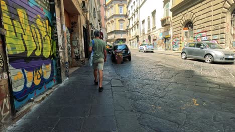 man strolls past vibrant street art in naples