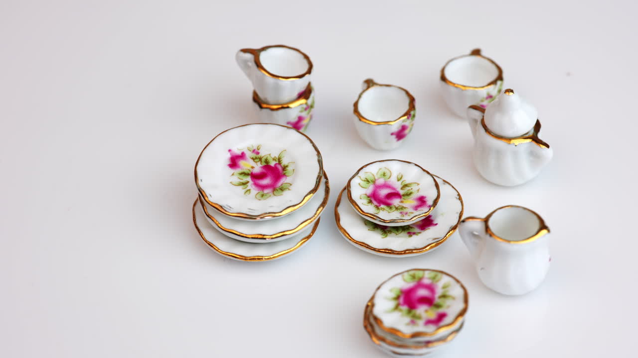 Rotating crockery with bright colorful flowers. Beautiful miniature dishes at white background. Close up.