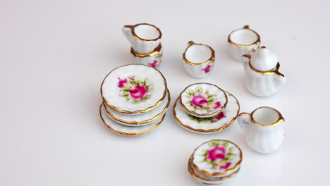 rotating crockery with bright colorful flowers. beautiful miniature dishes at white background. close up.
