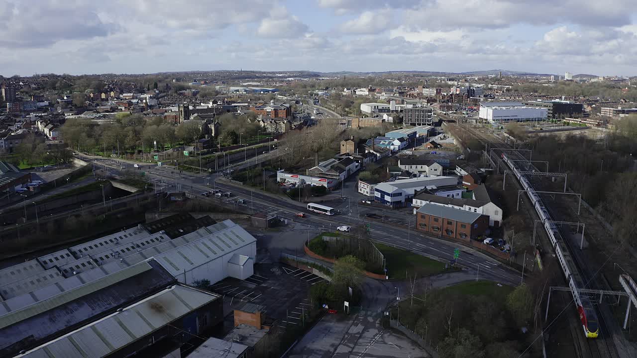 Luftoptagelse af tog, der nærmer sig Stoke on Trent togstation i Midlands, ved kanalen, vandkanten og A50 motorvejen, et midtpunkt for pendlere, der rejser nord og syd gennem Storbritannien.