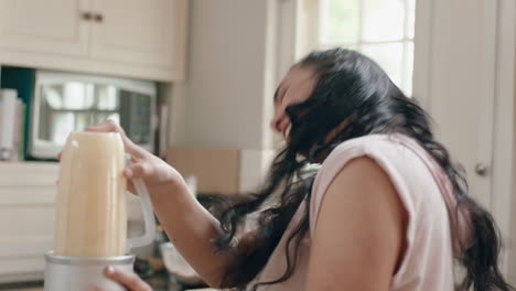 una adolescente con sobrepeso feliz bailando en la cocina haciendo un batido divirtiéndose celebrando una dieta saludable en casa disfrutando del compromiso de estilo de vida