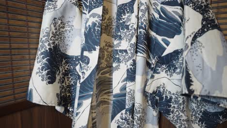 Vista-Recortada-De-Un-Kimono-Estampado-En-Azul-Y-Blanco-Que-Cuelga-Sobre-El-Fondo-De-La-Pantalla-Shoji