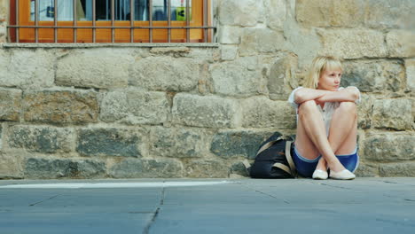 a tired tourist sat down to relax on the sidewalk in the old part of the city of barcelona