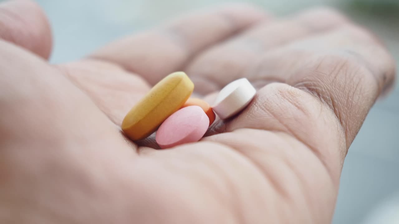 A Hand Holding Various Colorful Pills