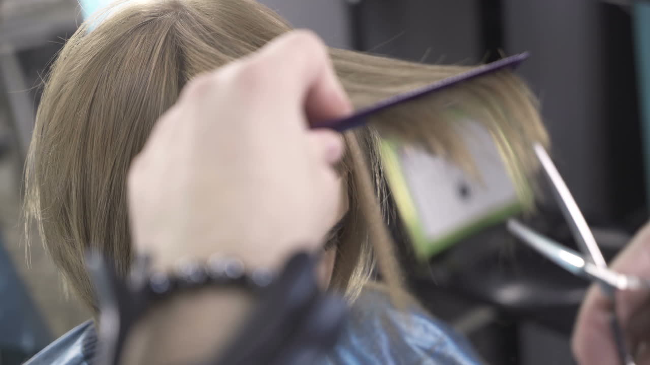 Hairdresser cutting hair of her customer at the hairdressing salon
