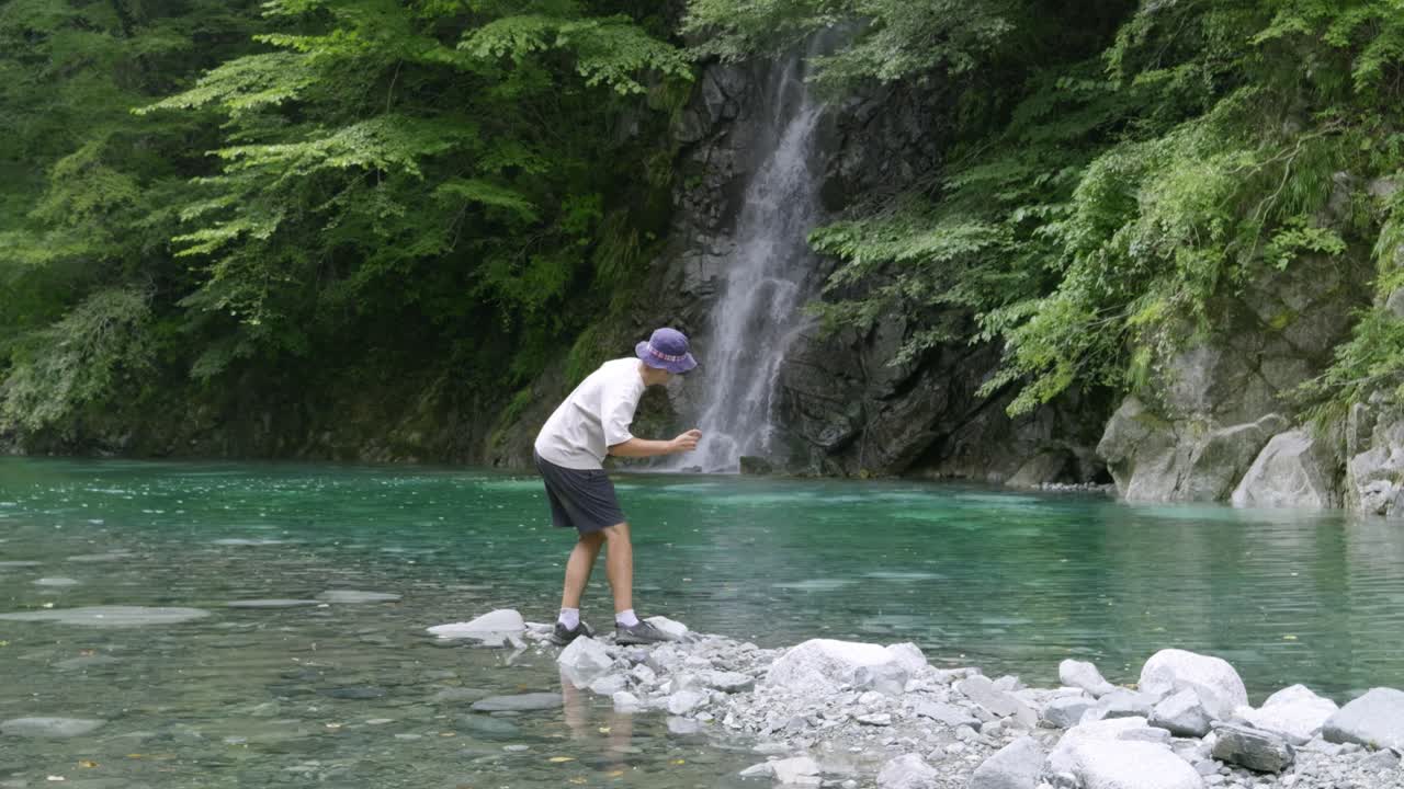 Young male hiker walking through natural scenery in lush greenery