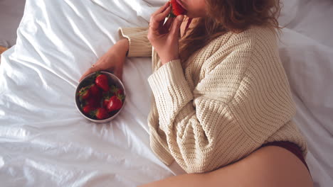 Vista-Recortada-De-Una-Mujer-Sexy-Comiendo-Fresas-Frescas-Mientras-Está-Acostada-En-La-Cama