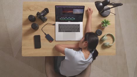 top view of asian woman editor sleeping while sitting in the workspace using a laptop next to the camera editing the video at home