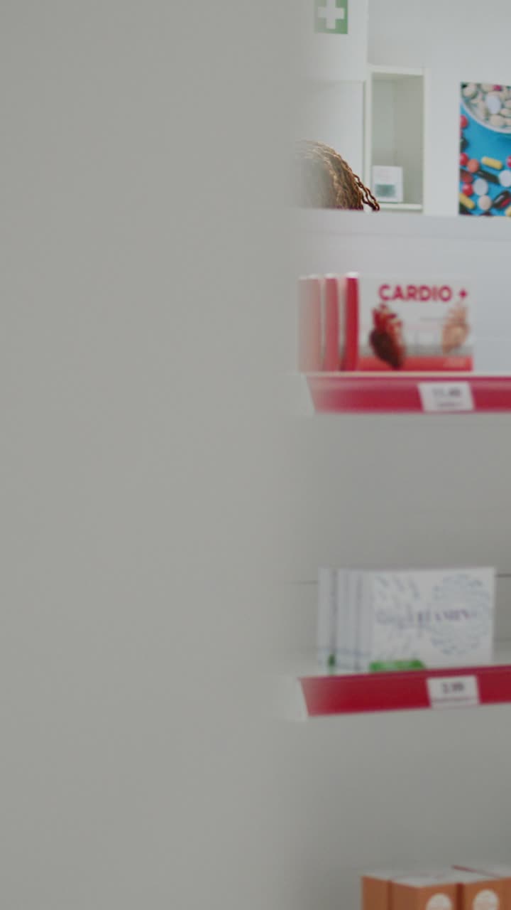Video verticale: cliente donna che prende confezioni di pillole dagli scaffali di una farmacia per acquistare farmaci con prescrizione
