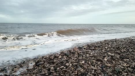 Sandige-Wellen-Stürzen-In-Zeitlupe-Auf-Den-Kiesstrand-Von-Rhyl