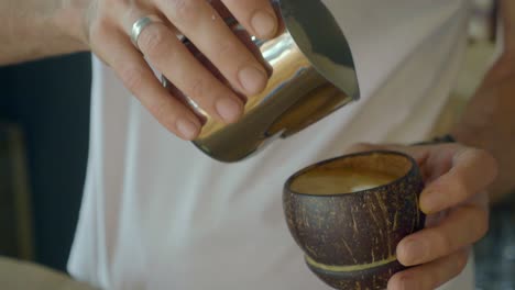 barista making a latte in a coconut shell cup