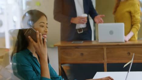 female graphic designer talking on mobile phone at desk 4k
