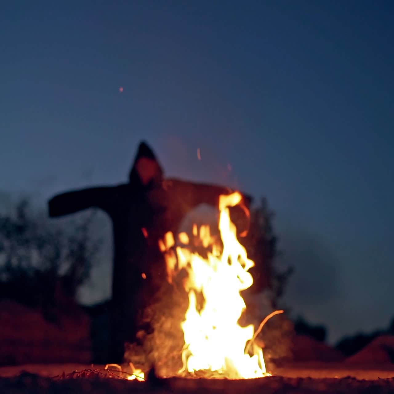 Horrible atmosphere at night outside. Bright flame with orange sparkles and dark nightmare with outstretched arms. Fright concept.