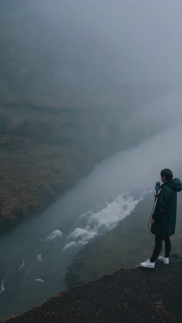 woman with microphone at a waterfall in foggy iceland
