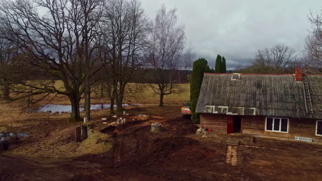 industrial digger working in remote countryside homestead, aerial follow view