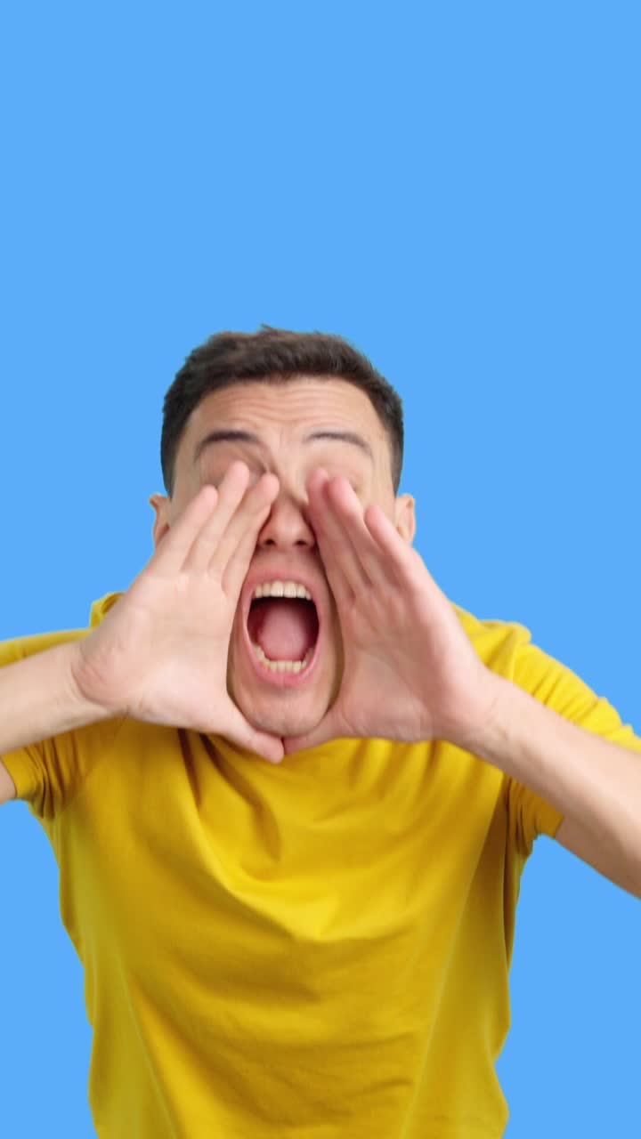 Excited man in yellow shirt on blue background