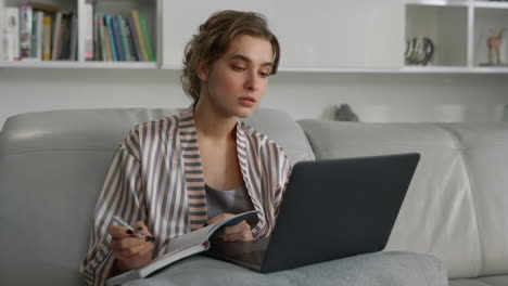 smiling girl studying home watching online university class in pajamas closeup.