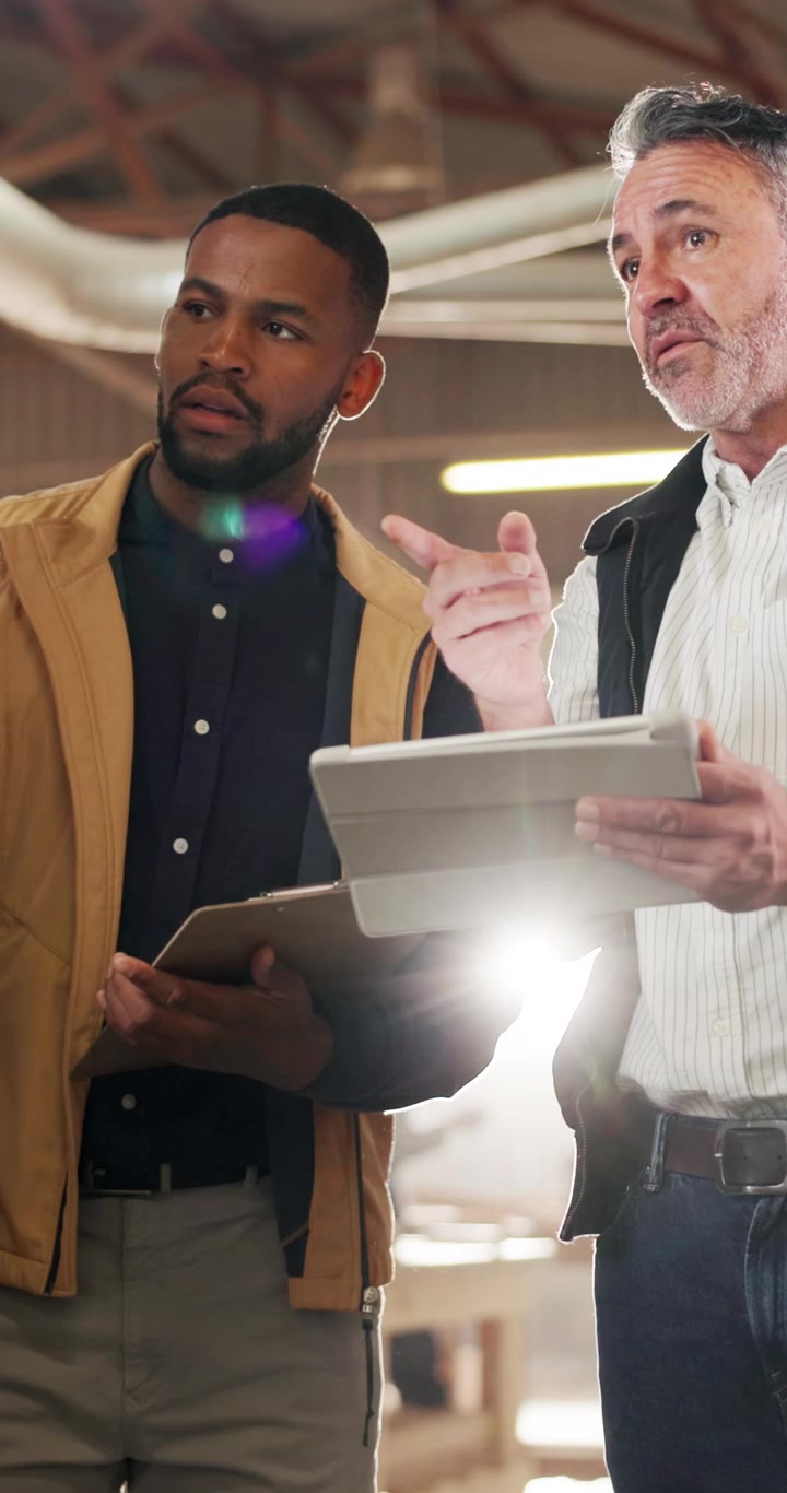 Two Men Discussing Project Details on Tablet in Workshop