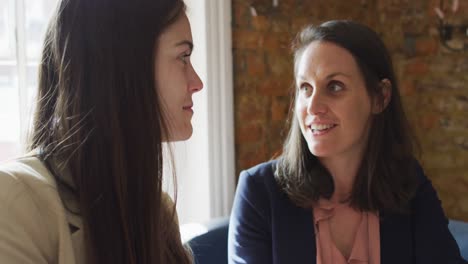 portrait of two caucasian businesswomen sitting at table, talking, having business meeting