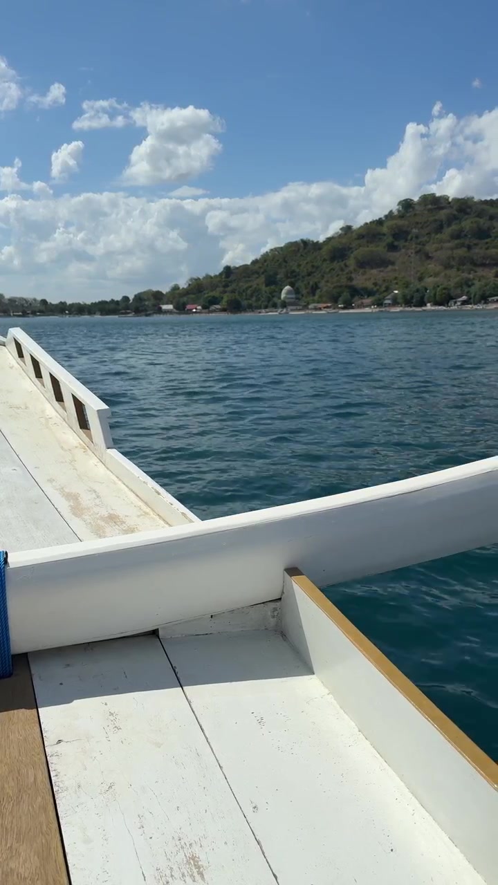 Vista dalla prua di una barca tradizionale in navigazione verso un'isola tropicale