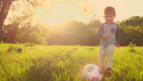 Junge-Steht-Bei-Sonnenuntergang-Mit-Einem-Fußball-Auf-Dem-Gras.