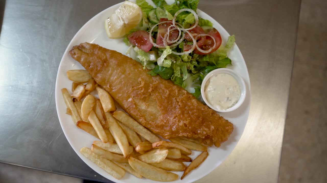 Crispy fried fish served with fresh salad and fries at local seafood eatery in the afternoon