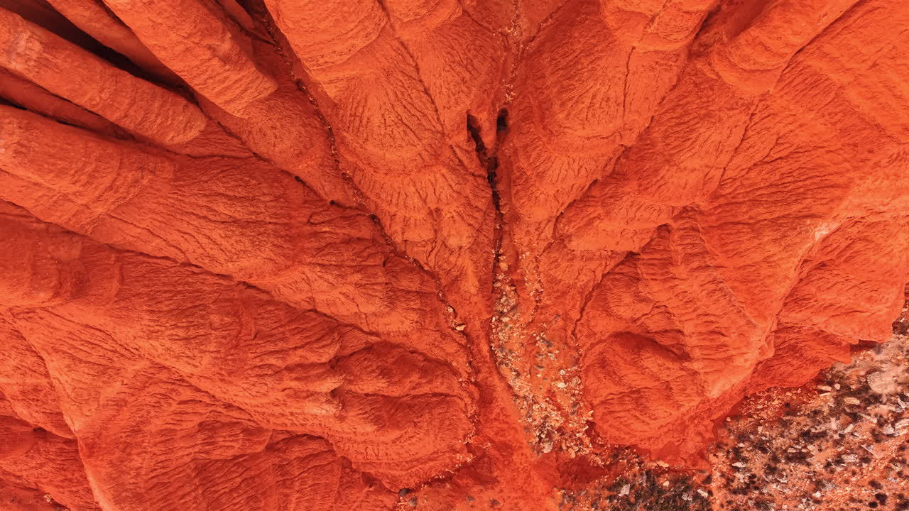 Vista aerea con drone di una gola di argilla rossa. Vista verticale con drone di una gola di argilla rossa erosa con un canale stretto, pietre sparse e pareti ripide.