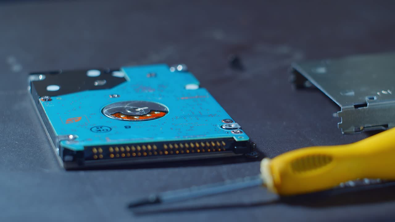 primer plano de un pequeño disco duro que se está reparando en una mesa un pequeño tornillo está siendo apretado por un pequeño destornillador
