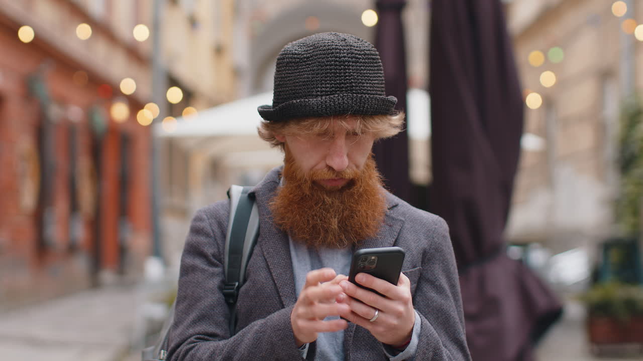 Mand bruger smartphone til at finde en rute på et kort i en mobil navigationsapp, hvorefter han går